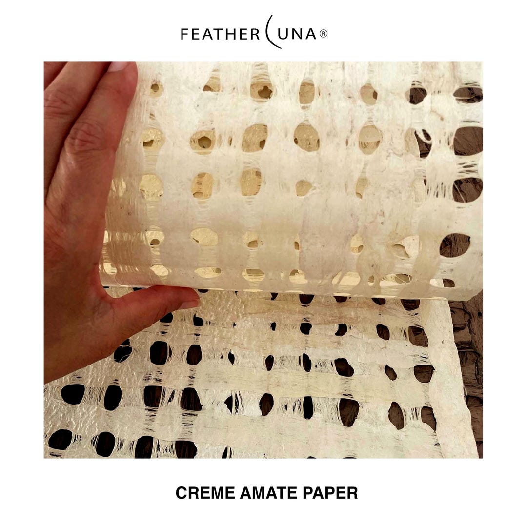 A hand lifting a sheet of Crème amate paper, light passing through its open grid
