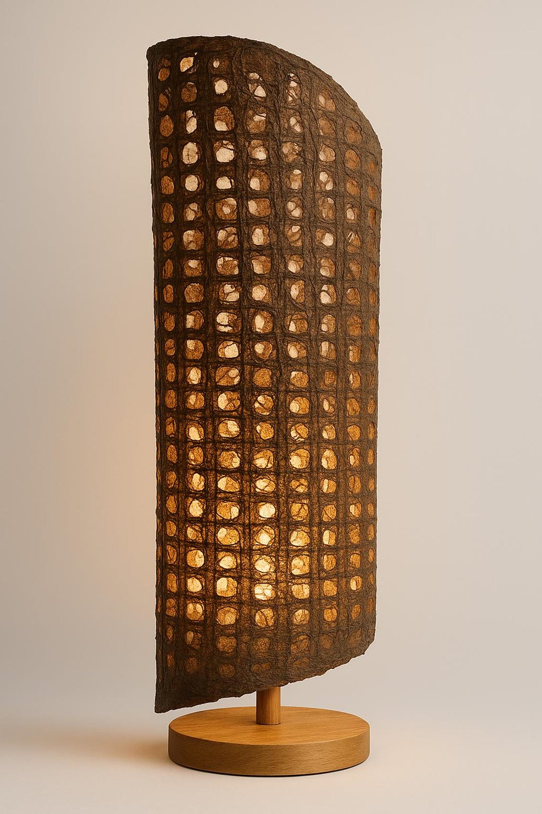 A tall curved panel of Café amate paper glowing with warm light, on a round wooden base