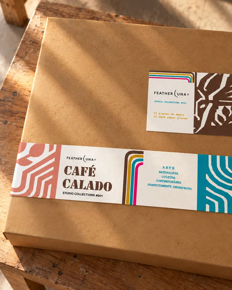 The Café Calado box in kraft card, wrapped in bright printed bands, on a sunlit wooden bench