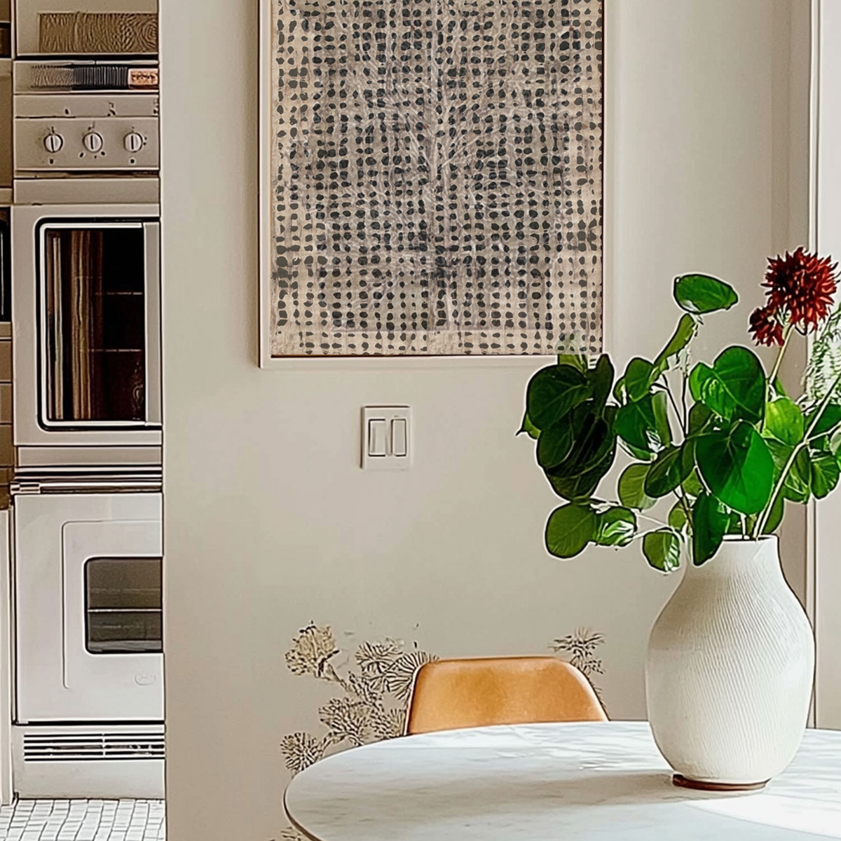 A framed amate paper panel on a kitchen wall above a round marble dining table