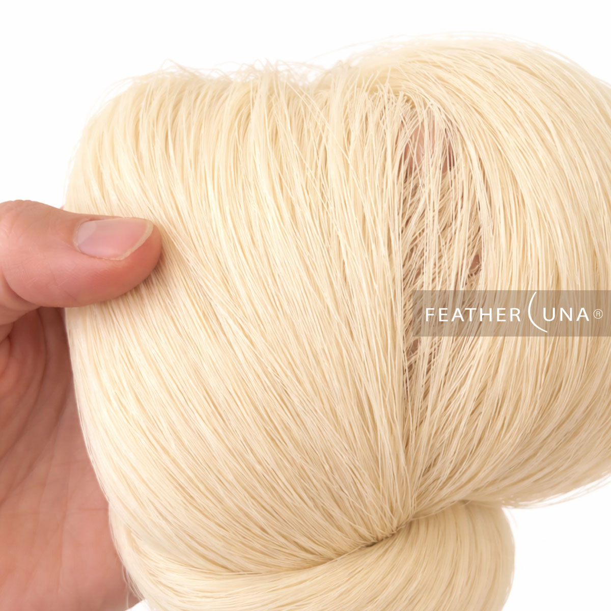 A hand holding a hank of untwisted cotton cord, its soft straight fibres close up