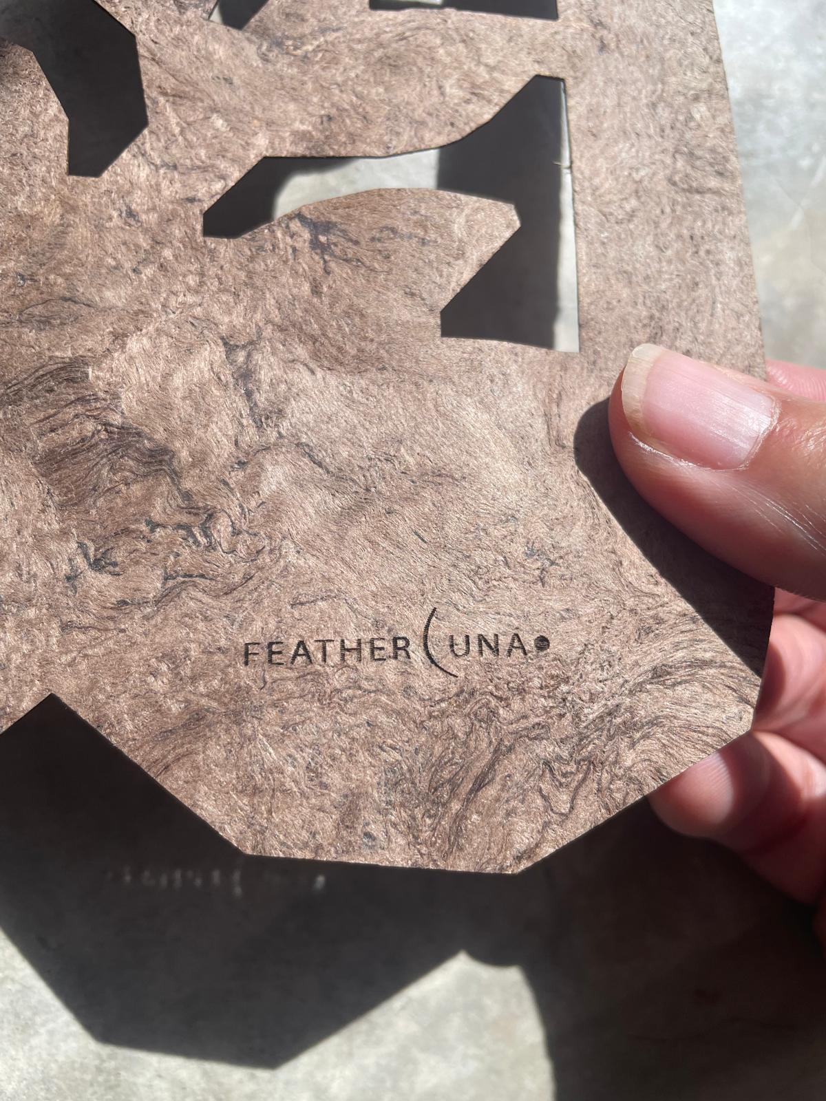 A hand holding a cut Café Calado piece, close up on the FeatherLuna mark in the bark